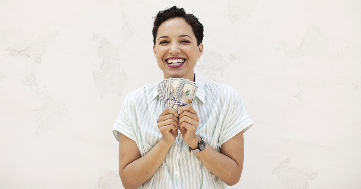 woman holding fanned out money and smiling