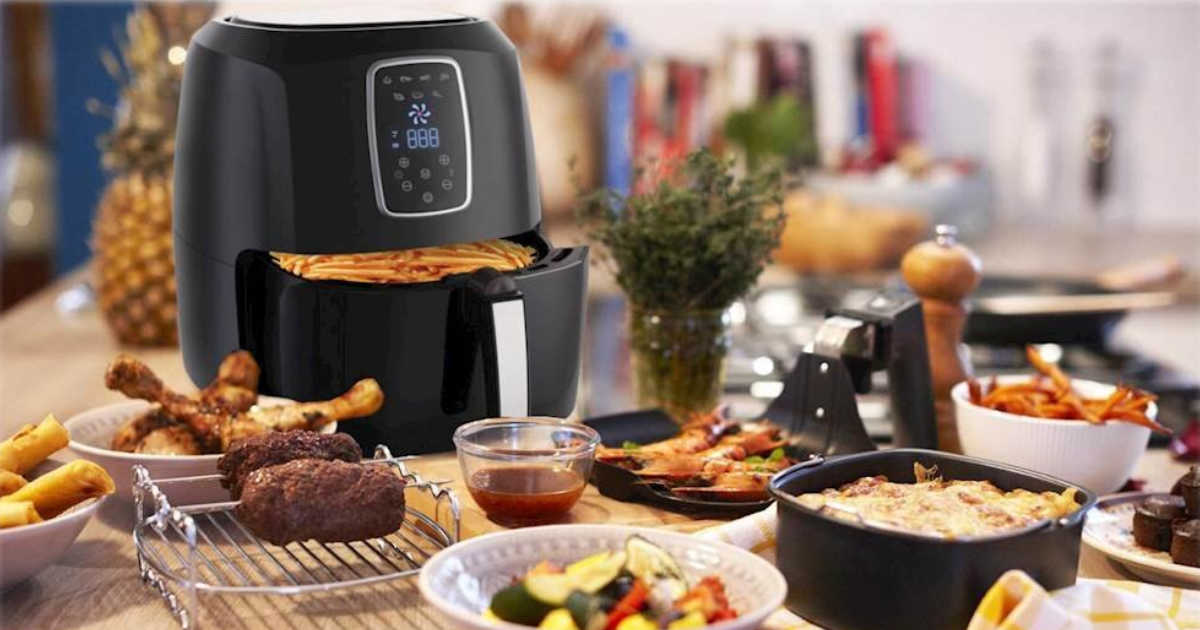 air fryer with fries in basket and a ton of food on the table