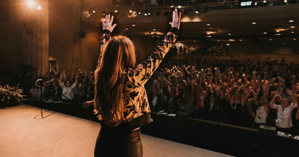 Rachel Hollis waving to the crowd from the stage