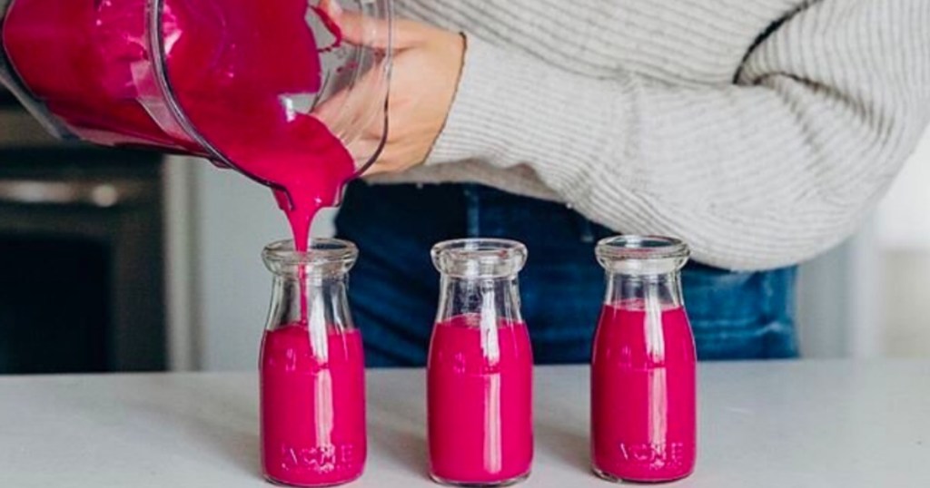 pouring red liquid into bottles from blender