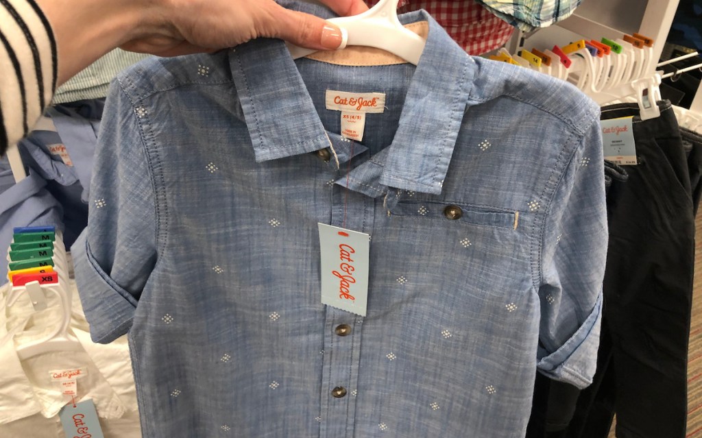 hand holding a button down dress shirt blue with white polka dot design