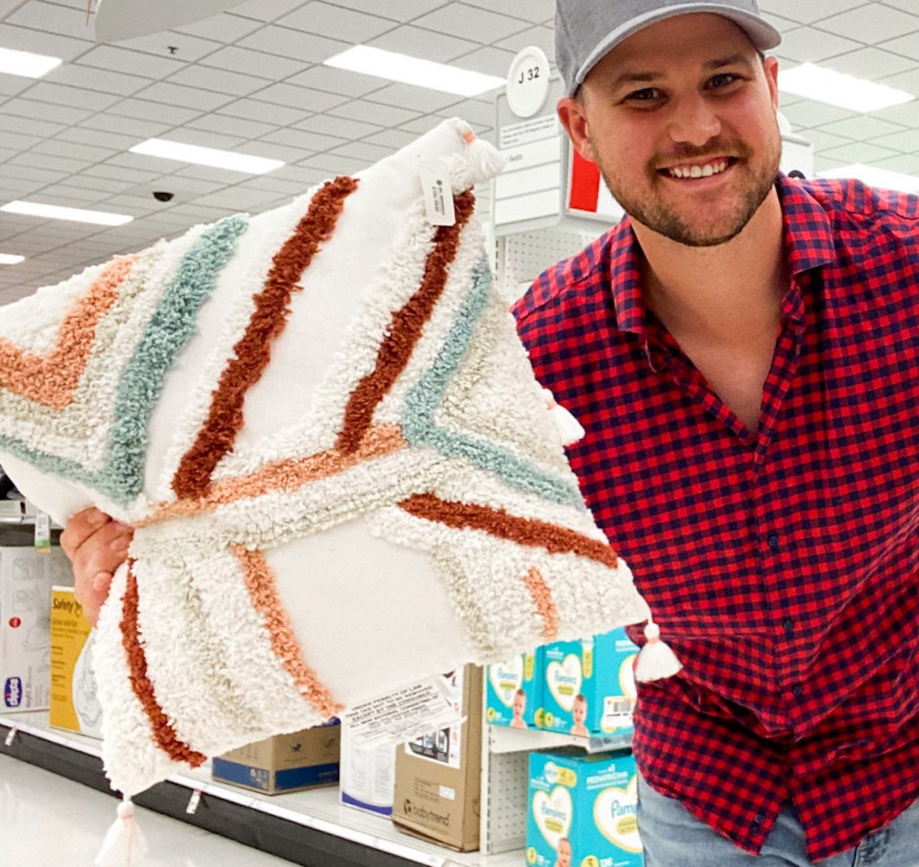 man holding colorful throw pillow in target store