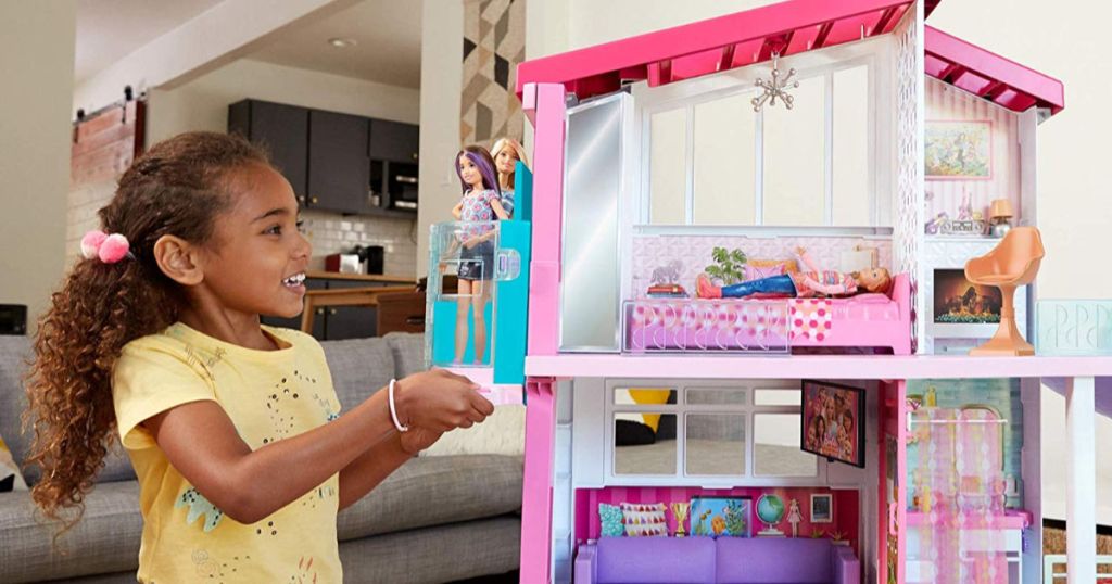 little girl playing with barbie dream house