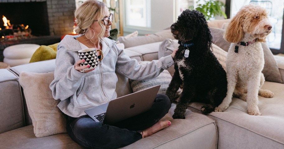 woman sitting on couch with coffee mug and two dogs