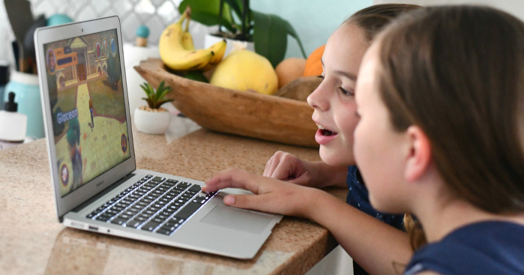 kids smiling and playing on a laptop