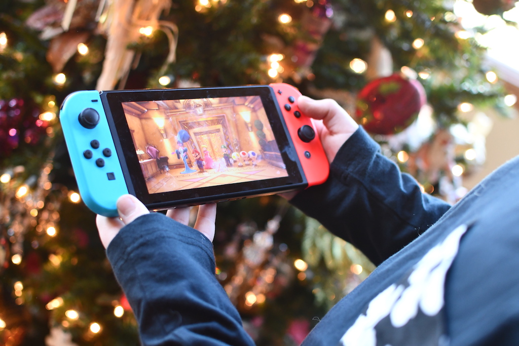 boy holding nintendo switch by crhistmas tree