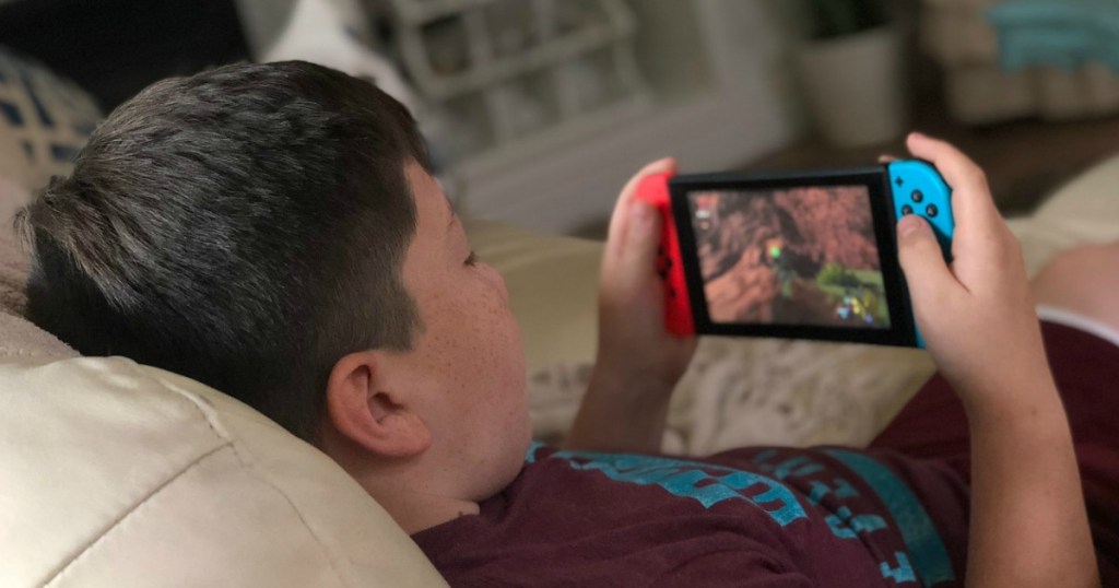 Boy laying on couch playing Nintendo Switch