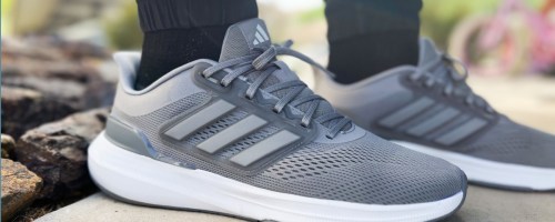 Picture of gray Adidas shoes being worn by a person.