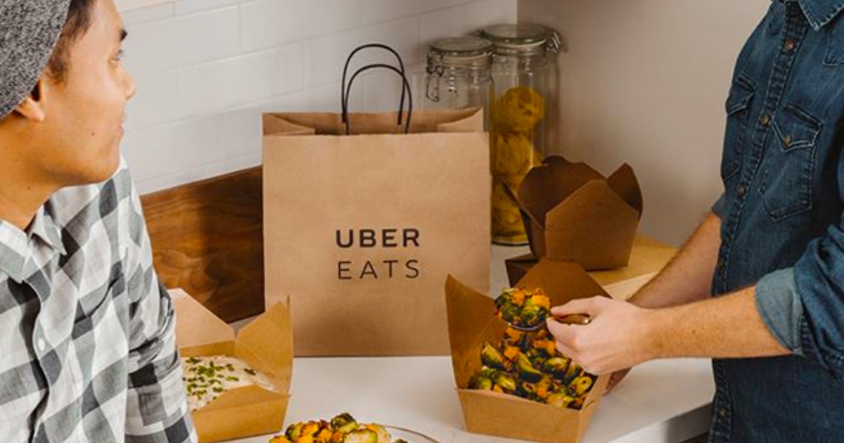 uber eats bag sitting on counter with food and people around it