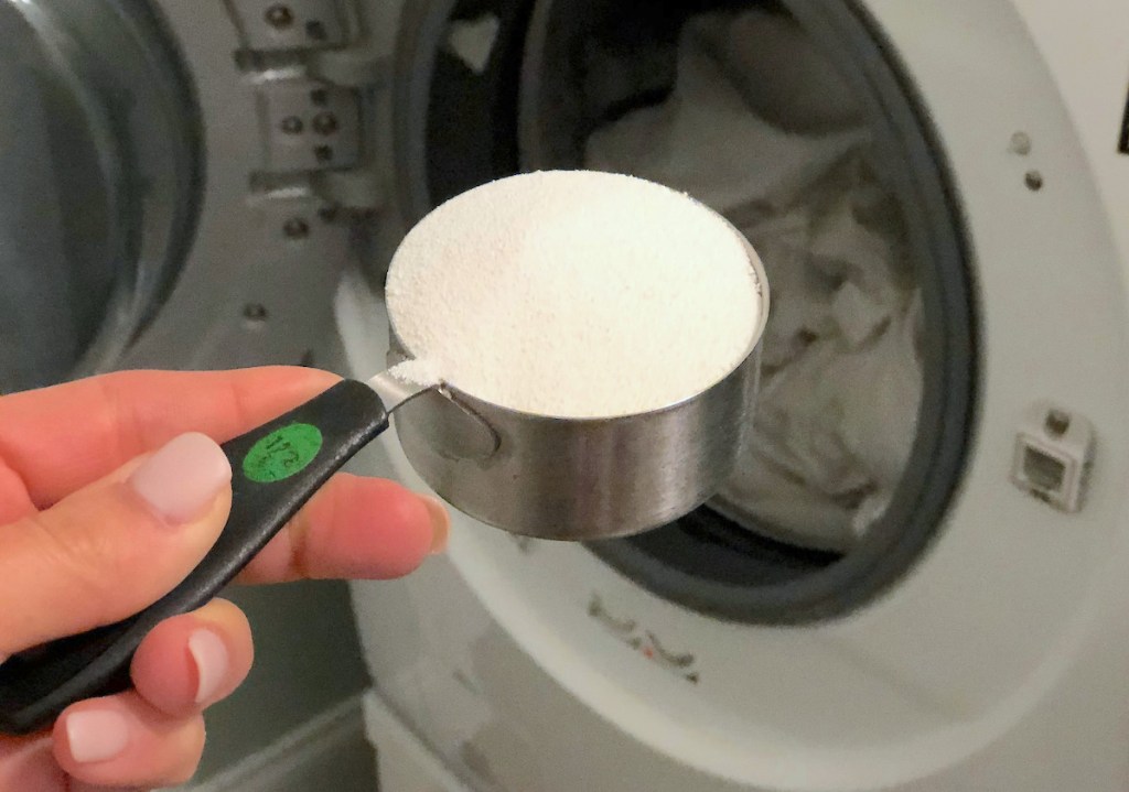 hand holding a dry measuring cup with white powder