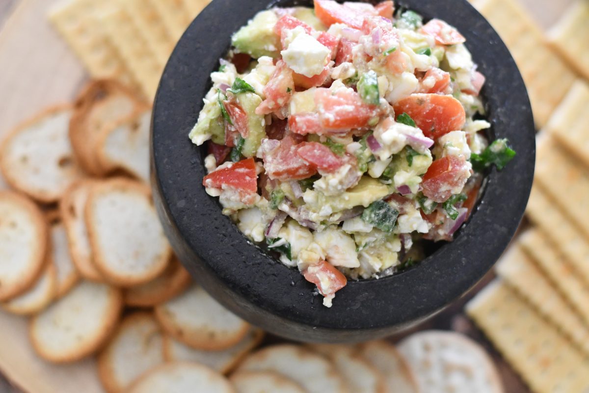 bowl of avocado tomato salsa served with crackers and melba toasts