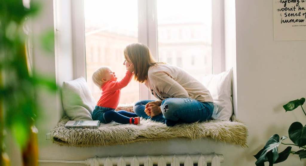 mom and baby sitting on a window sill bench talking showing affection