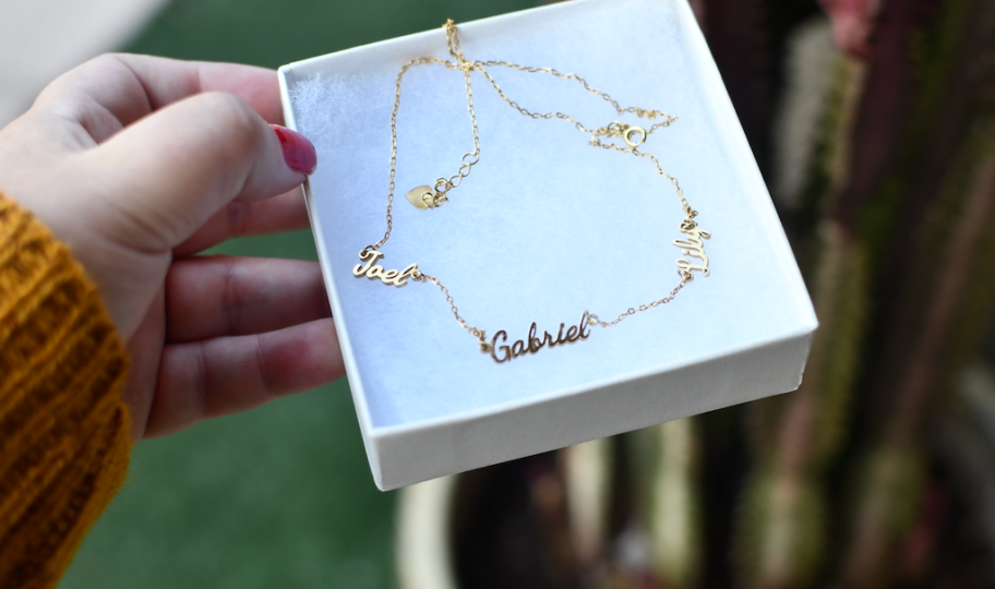 hand holding a box with a name necklace inside