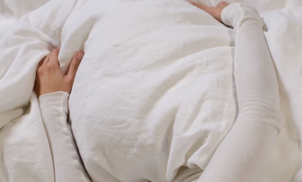 persons arms laying on white blanket 