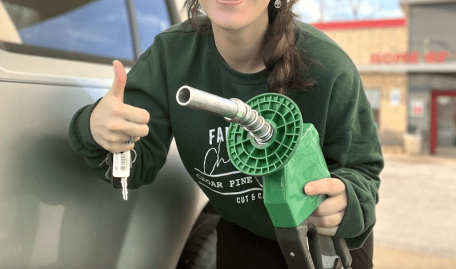 woman holding keys and gas pump next to car