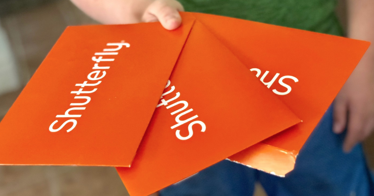 three Shutterfly envelopes held in hand outside