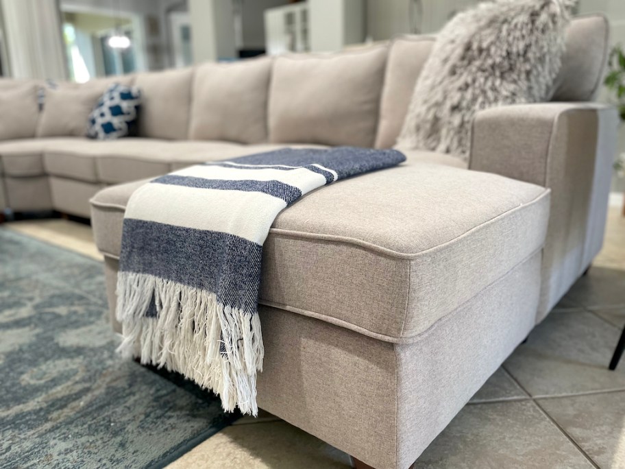 close up of beige sectional in living room with stripe throw blanket