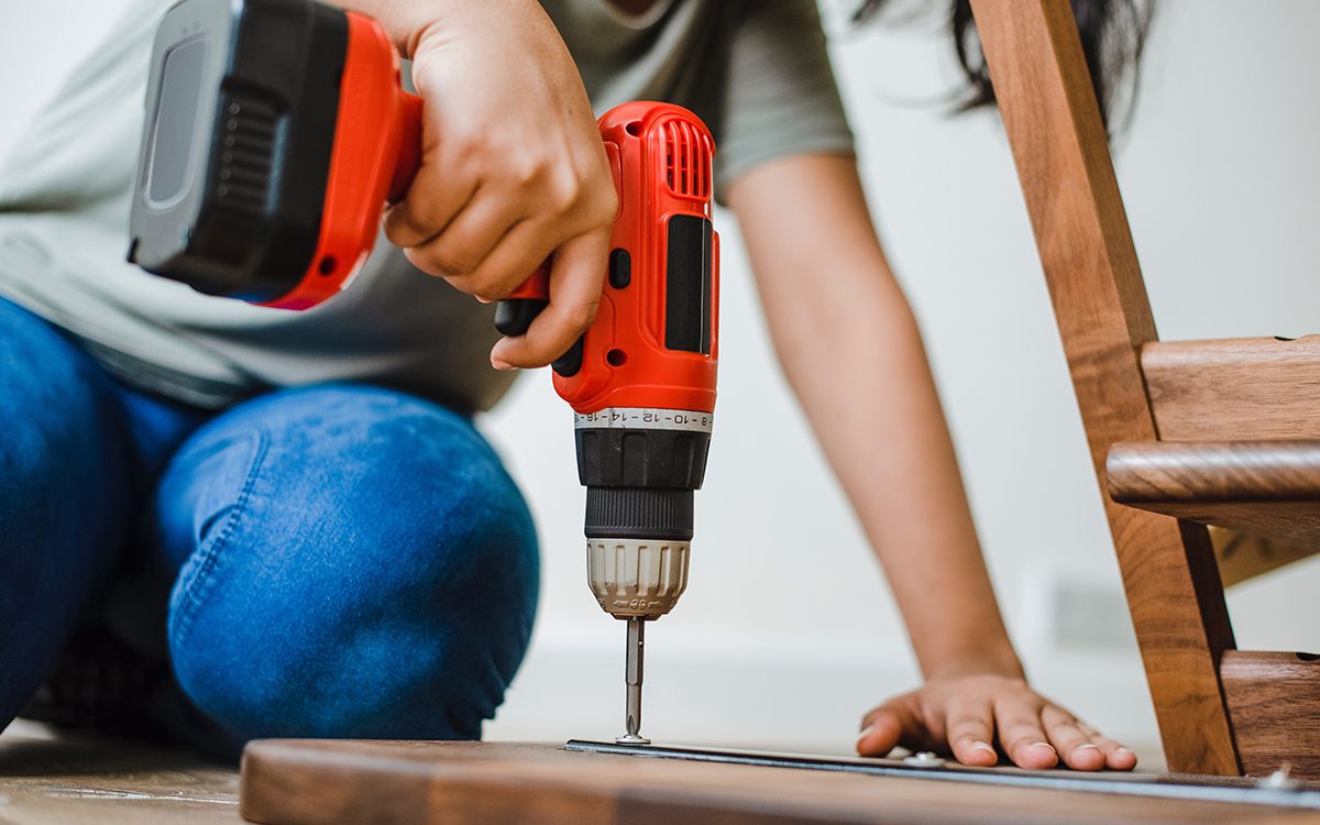 woman using a drill to assemble furniture