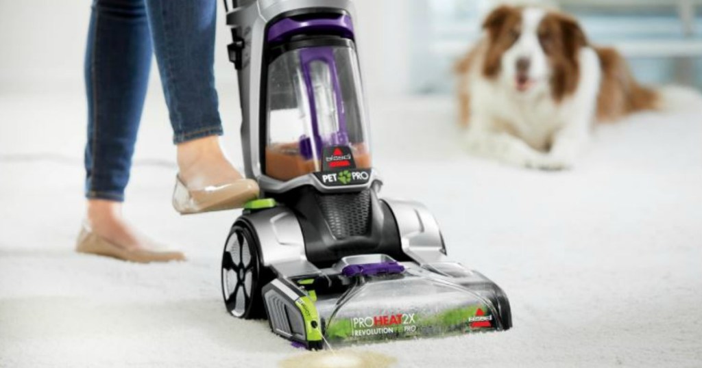 woman using a BISSELL ProHeat 2X Revolution Pet Pro Carpet Cleaner with dog in background