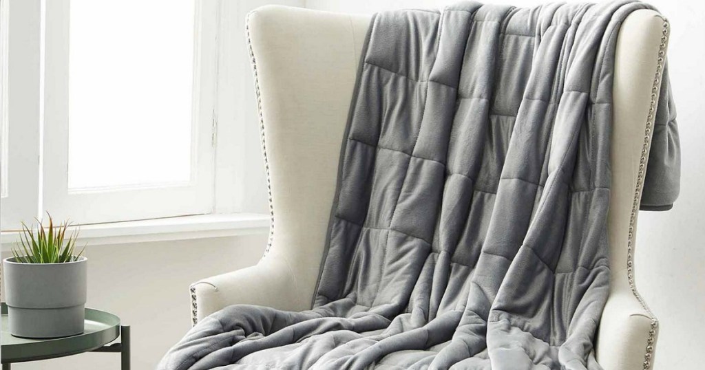 Weighted blanket draped over cream-colored chair in living room