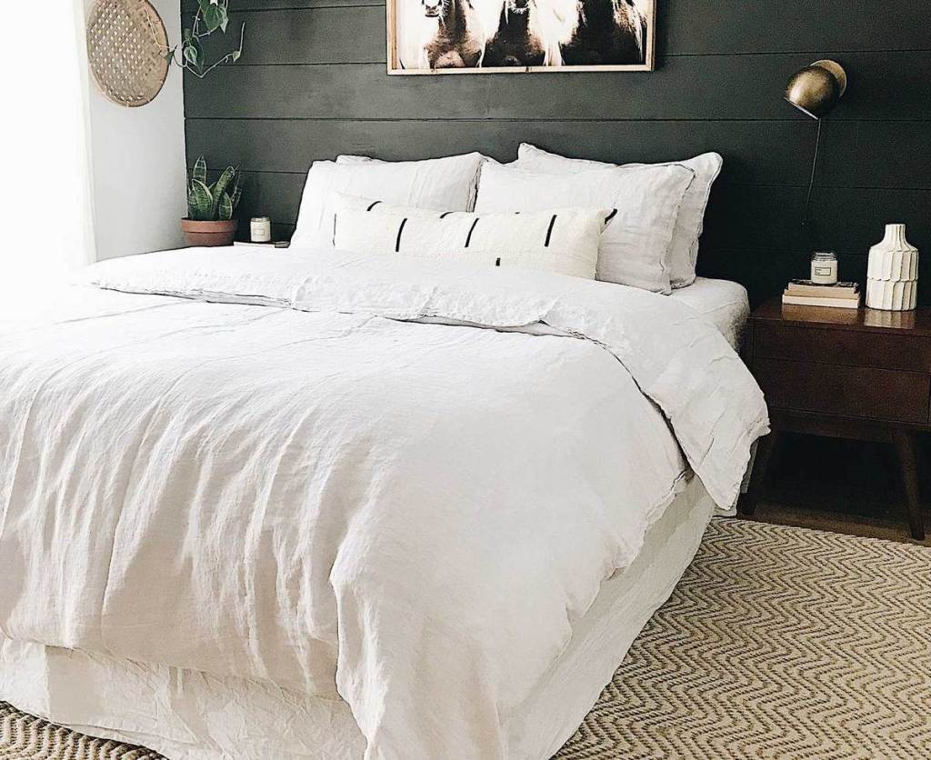 bedroom with white bed and pillows with dark accent wall behind it