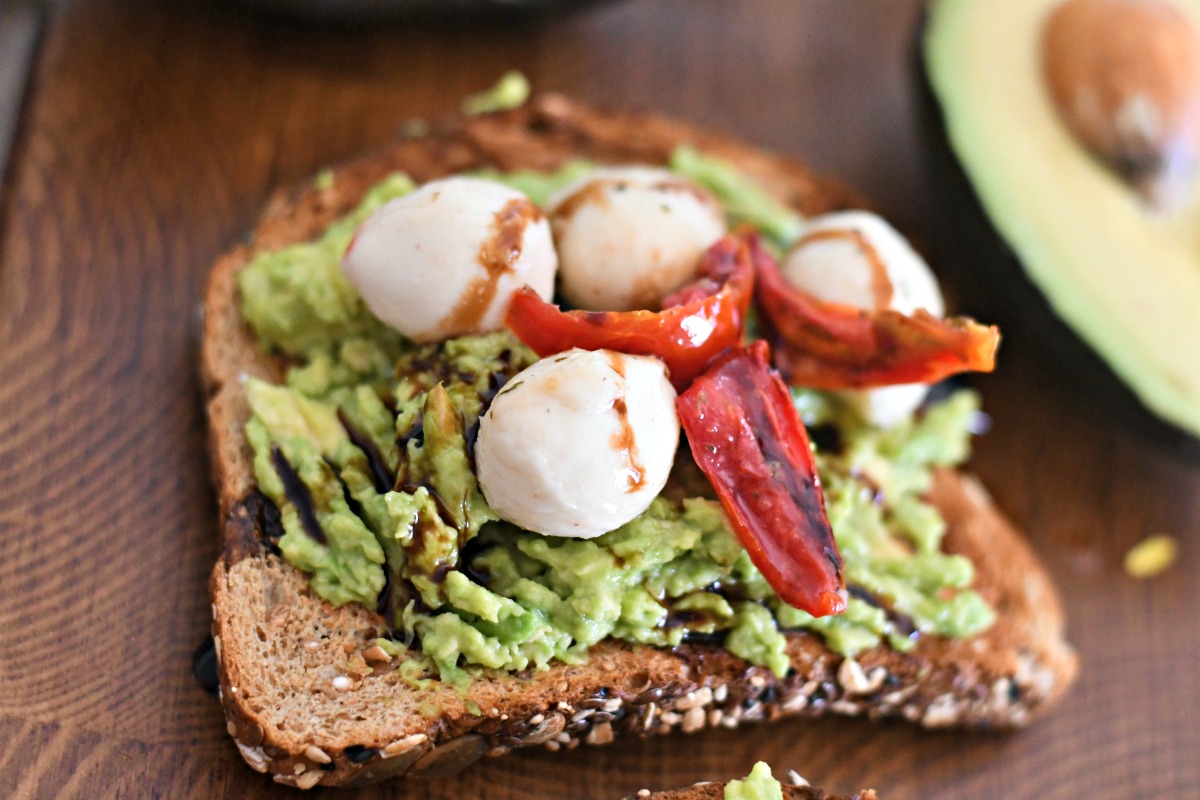 mozzarella cheese and roasted tomato avocado toast on a wood board 