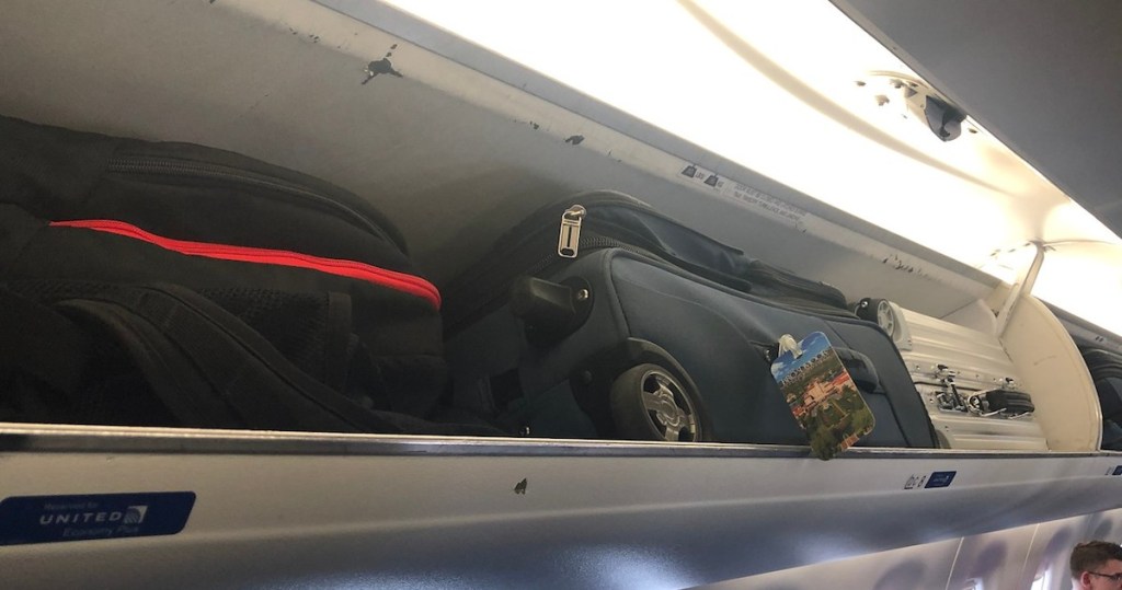 three suitcases luggage in overhead onlinepartment on airplane