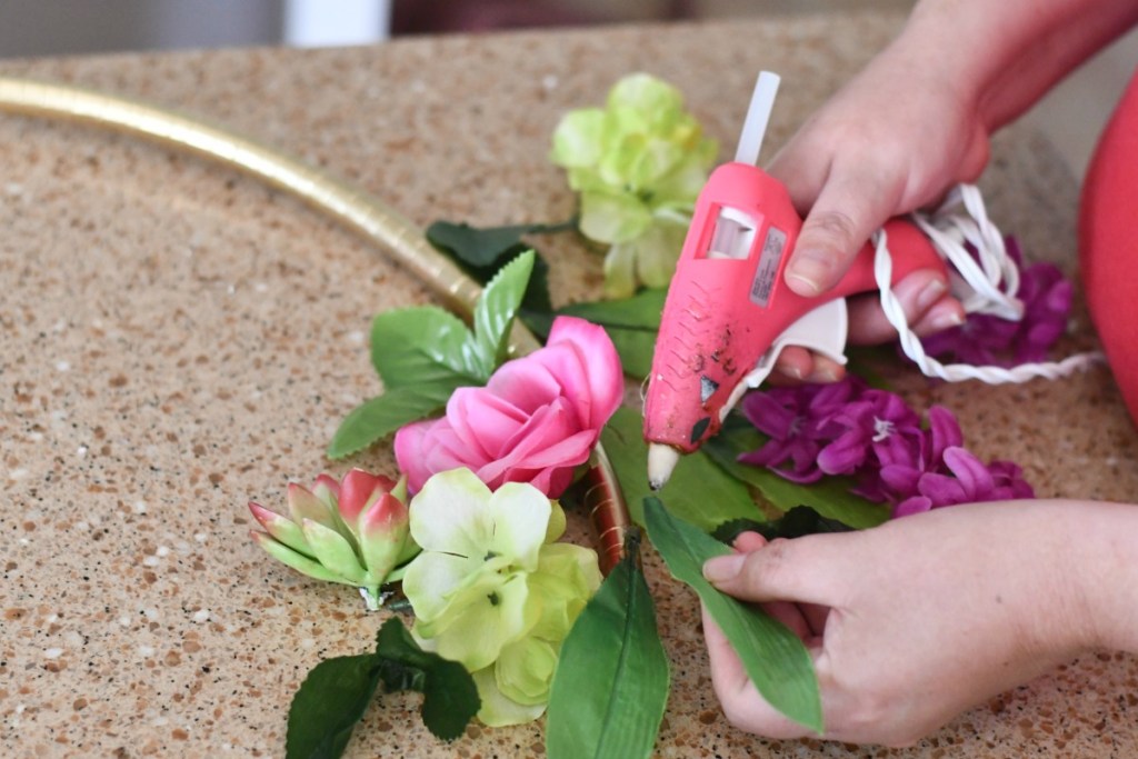 gluing faux leaves to a gold hula hoop photo display