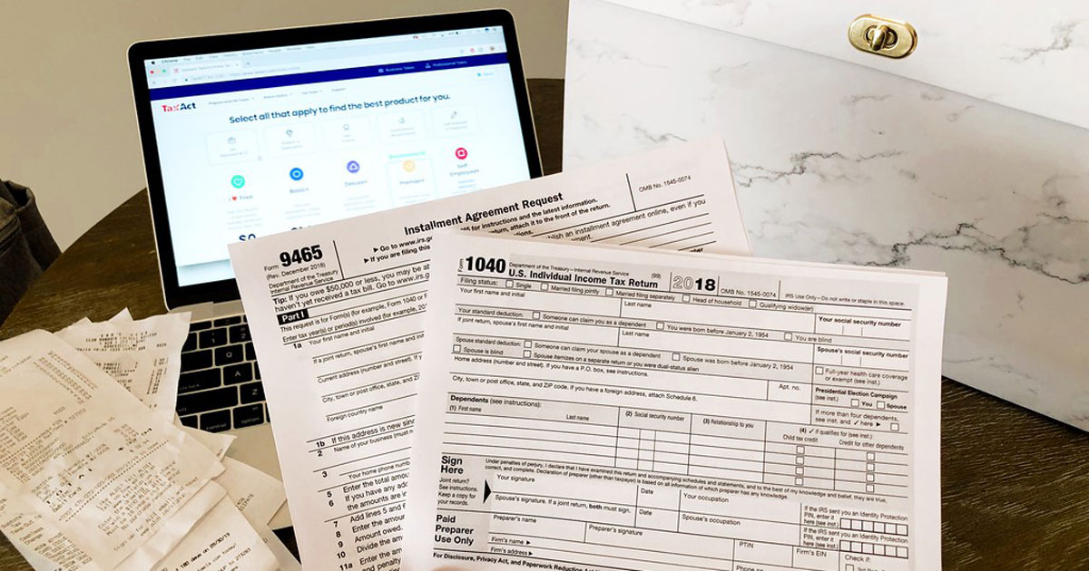 tax forms, receipts, and an open laptop