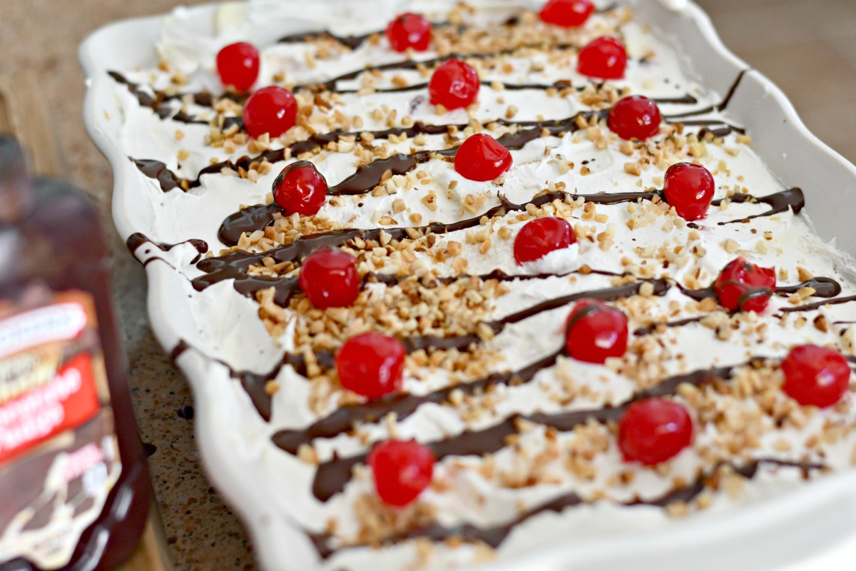 adding chocolate and cherries to banana split pudding dessert