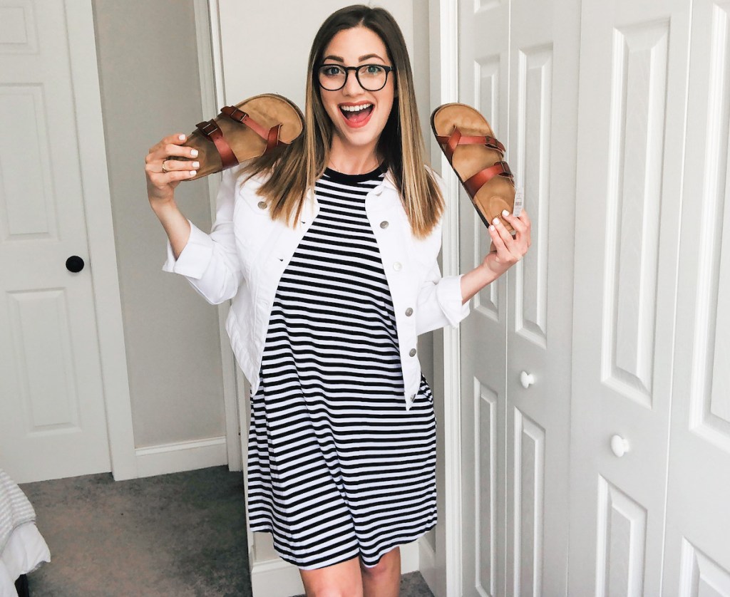 woman smiling holding pair of leather sandals