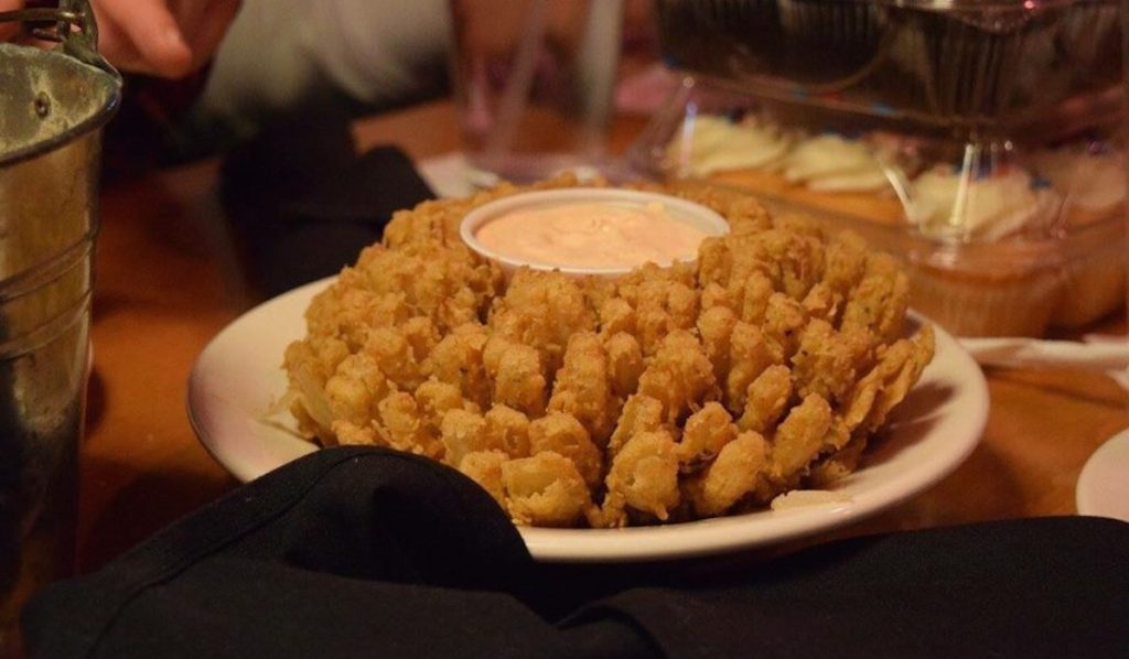 blooming onion with sauce in the middle sitting on plate