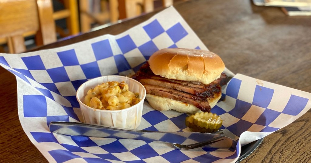 brisket sandwich and side of mac and cheese sitting in blue and white checked basket