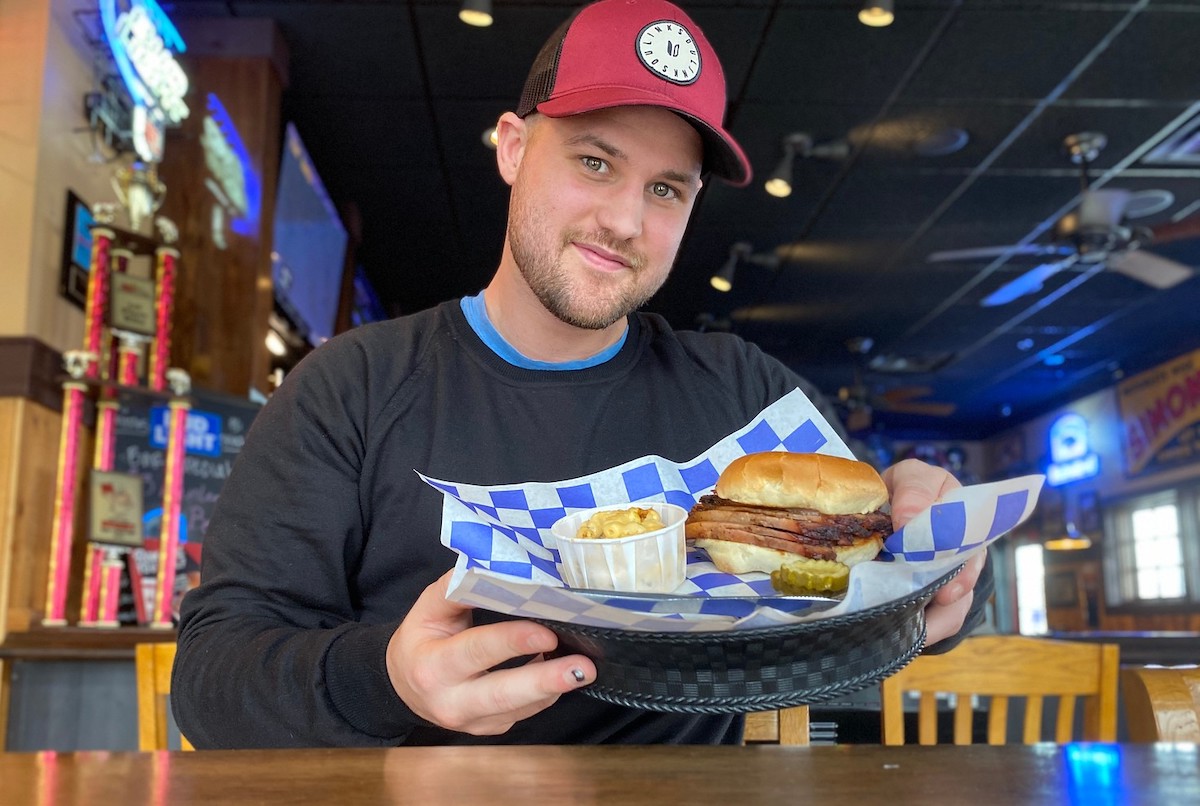 man sitting at table smiling holding a sandwich in basket because he got free food when you sign up for Dave's app