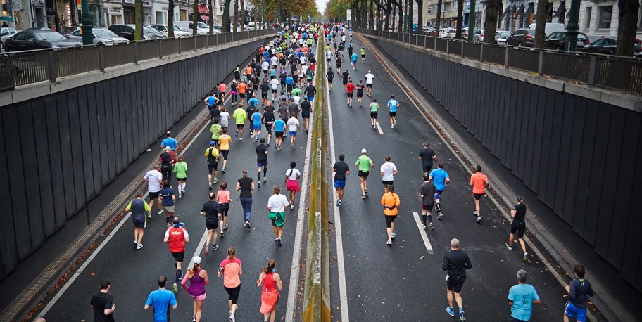 large group of people running on highway in organized race workout accountability app