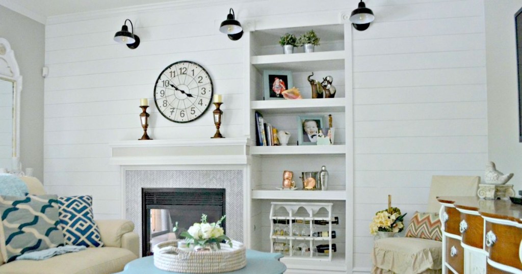 white shiplap wall with fireplace and white mantel with various home decor