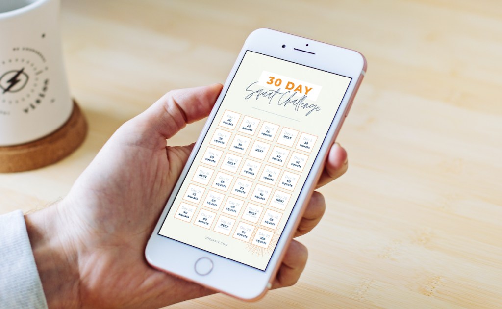 hand holding a cell phone with 30 day squat challenge on screen