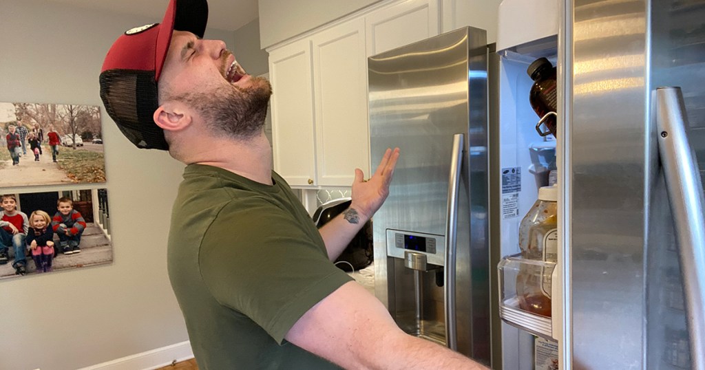 man holding up fridge door in agony