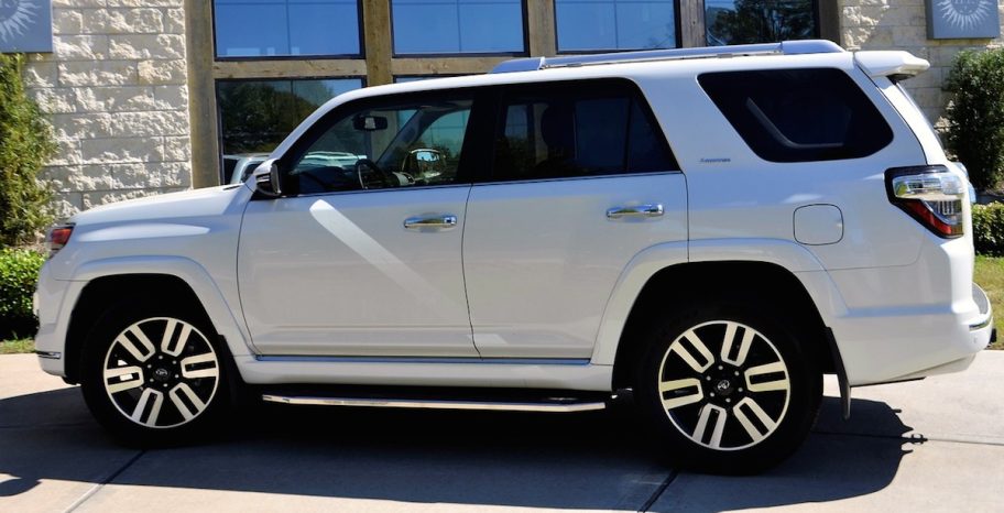 white toyota suv car sitting on cement road with building behind it