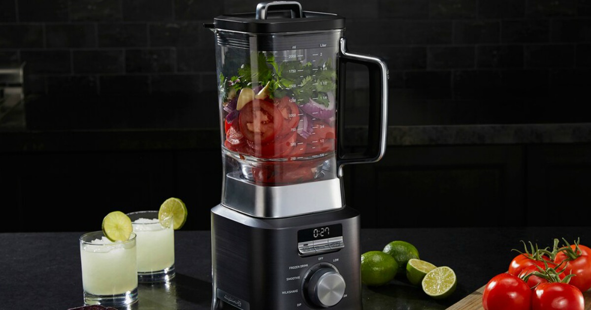 blender bleding veggies with drinks and limes beside it