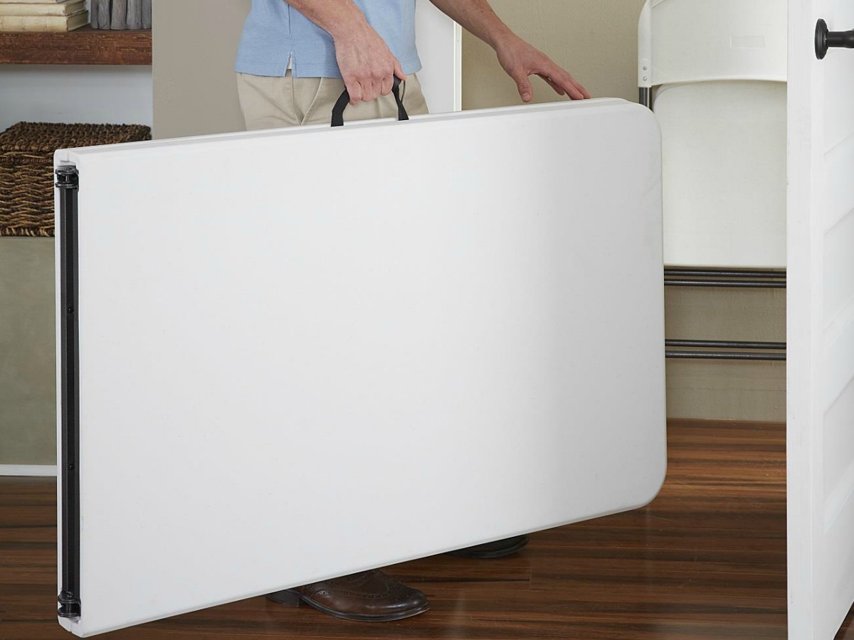 man carrying foldable table to closet