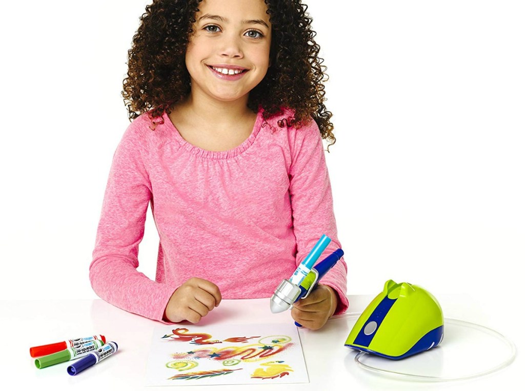 girl in pink shirt playing with a Crayola Air Marker Sprayer