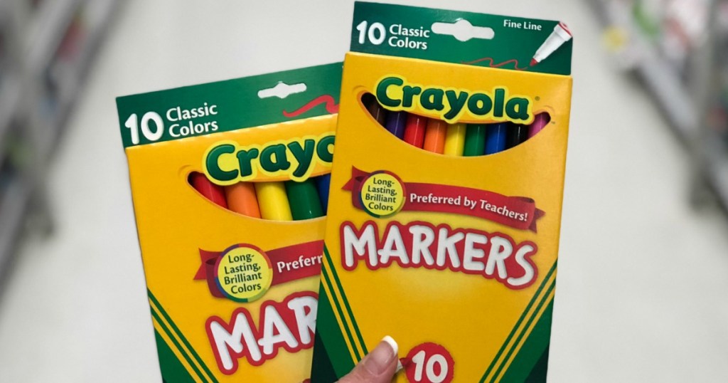 hand holding two packs of Crayola markers