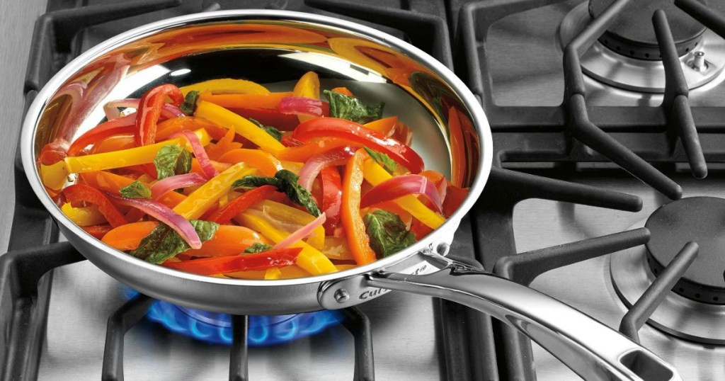 Cuisinart skillet with sliced peppers and onions over gas stove burner