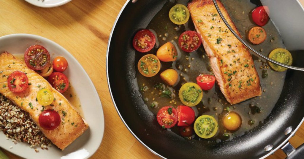 Farberware pan full of cooking vegetables next to plate of fish and rice