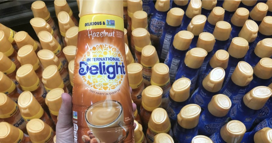 Large international delight creamer in hazelnut flavor being held over a cooler of creamers