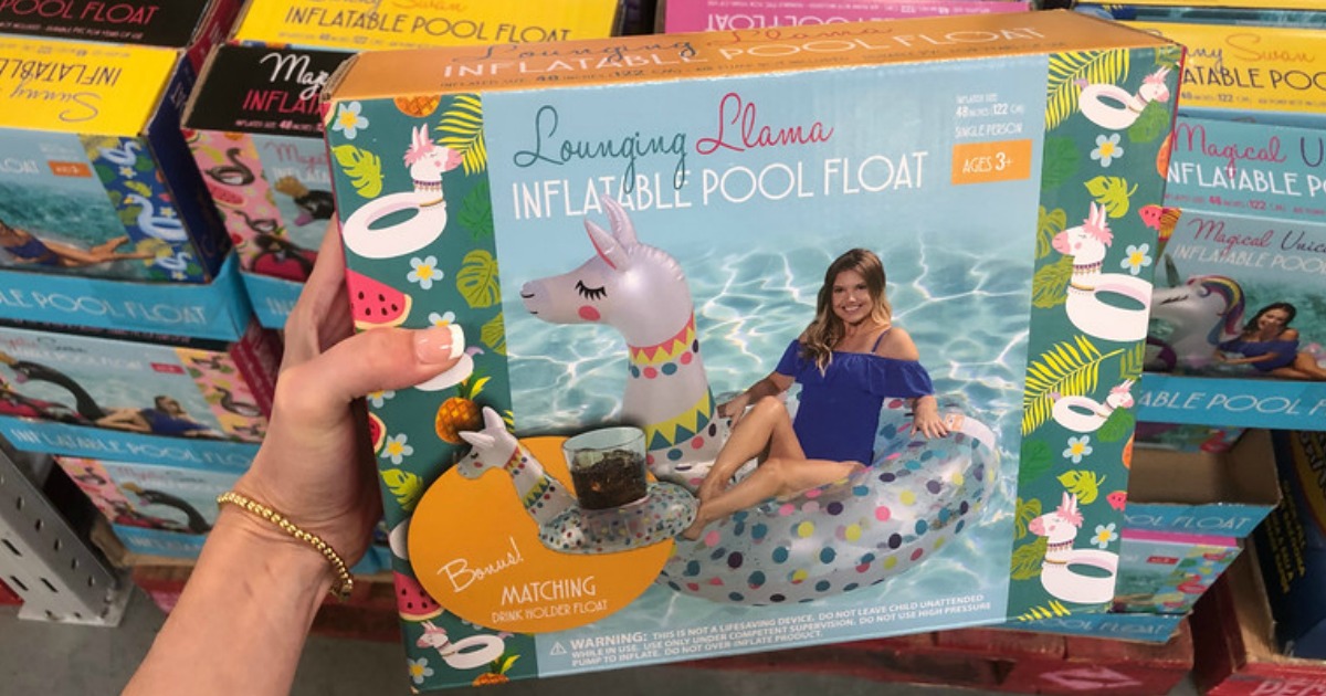 hand holding up lounging llama pool float with more floats behind it