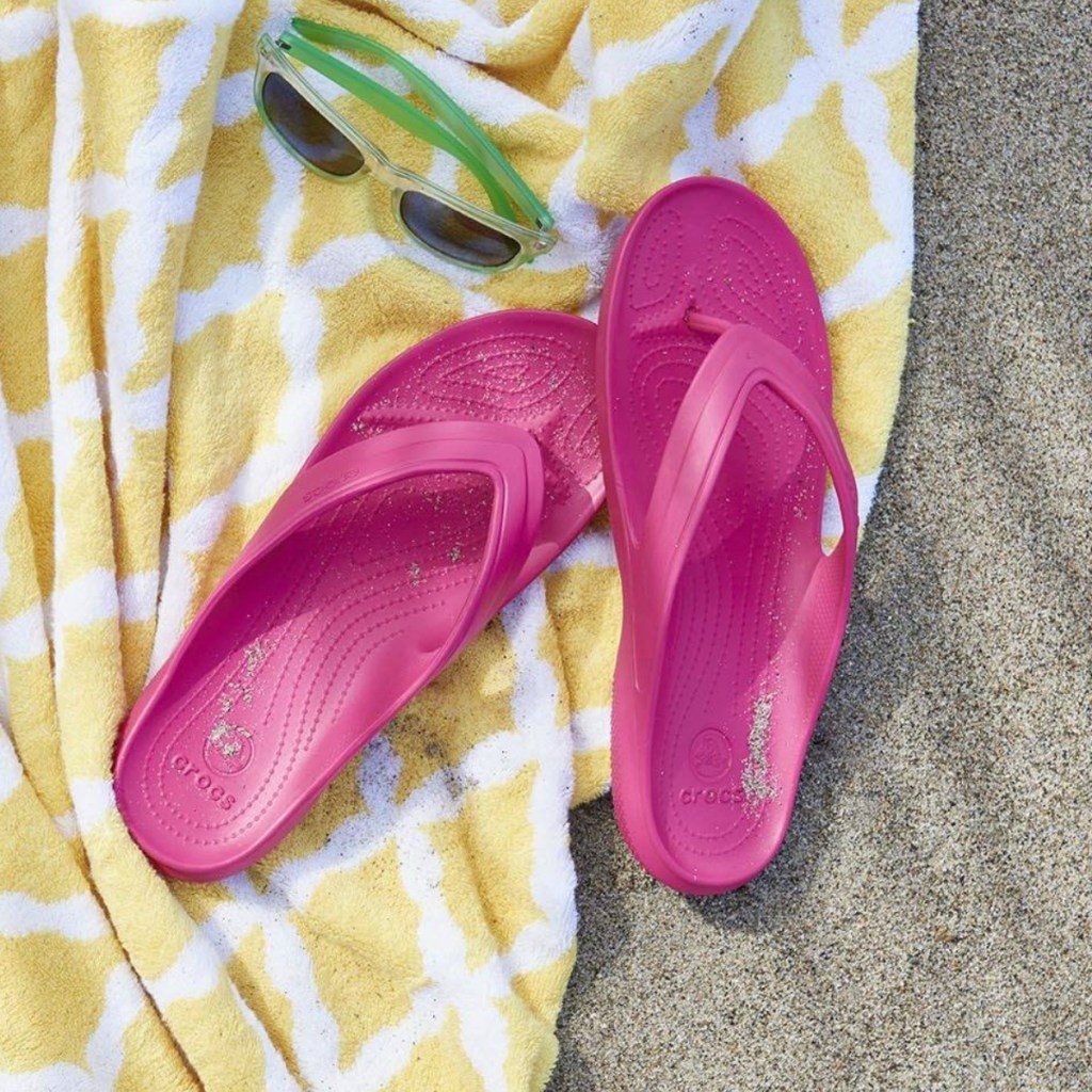 pink crocs sandals on yellow towel in the sand