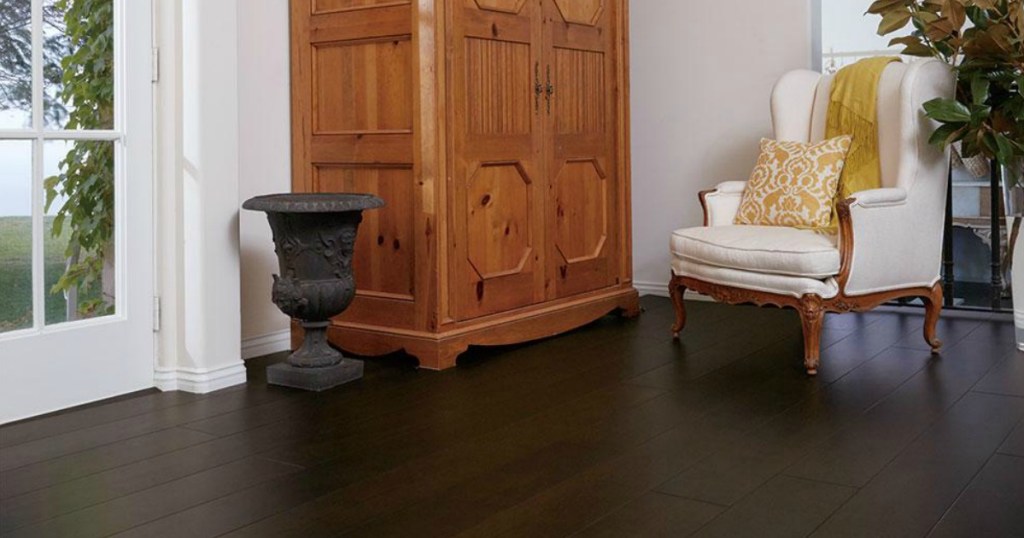 wide planks in a room with glass French doors, a cream chair and an armoire