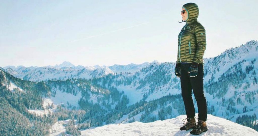 woman in green coat standing on mountain top